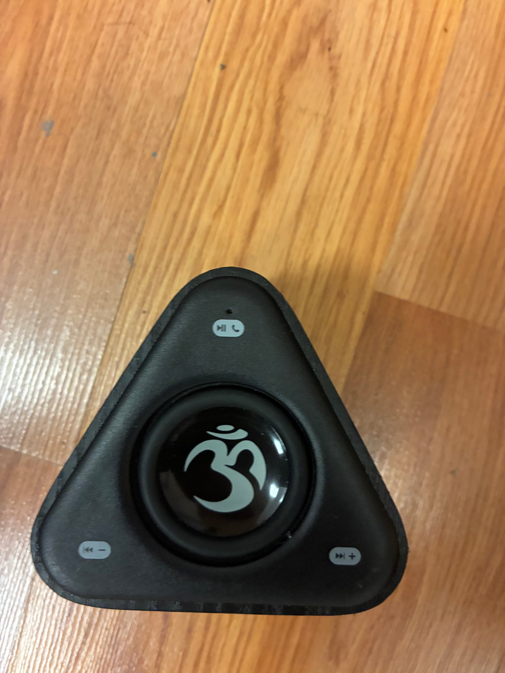 Black triangular device with a logo on a wooden surface